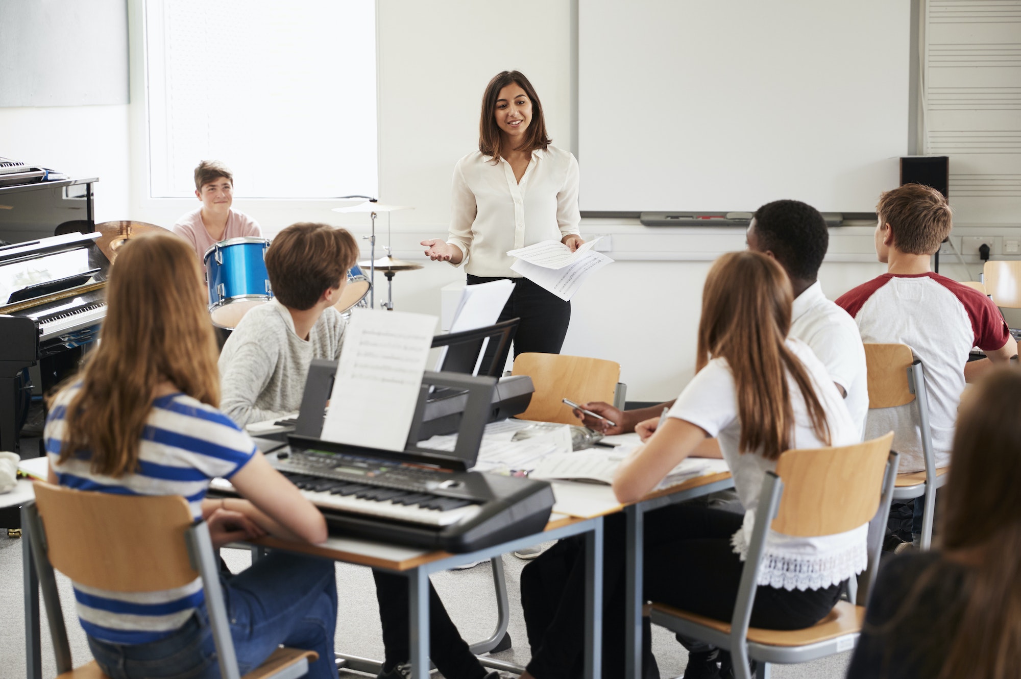 Teenage Students Studying In Music Class With Female Teacher